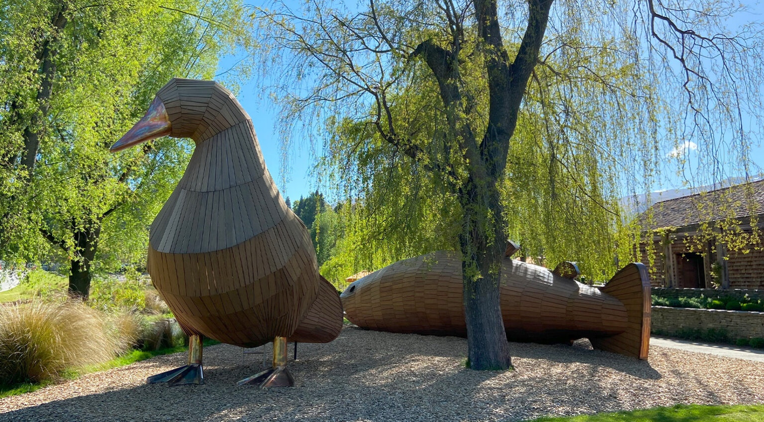Large timber duck and trout sculptures together in a landscaped park